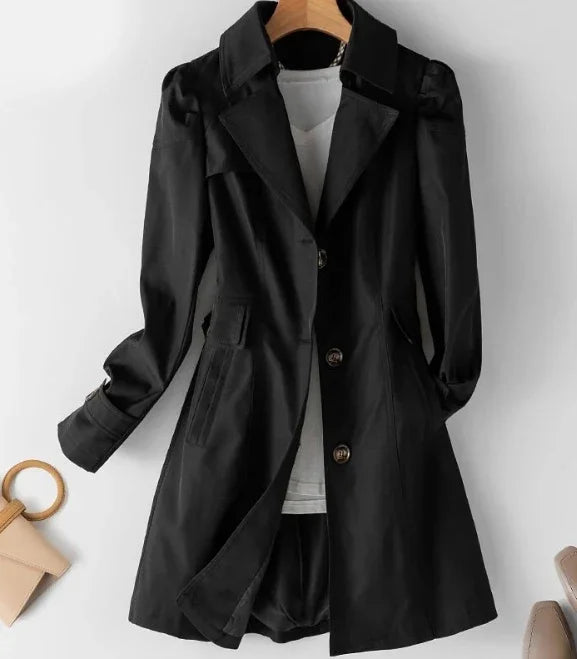 Black long-sleeve women's trench coat with buttons, displayed on hanger over white shirt