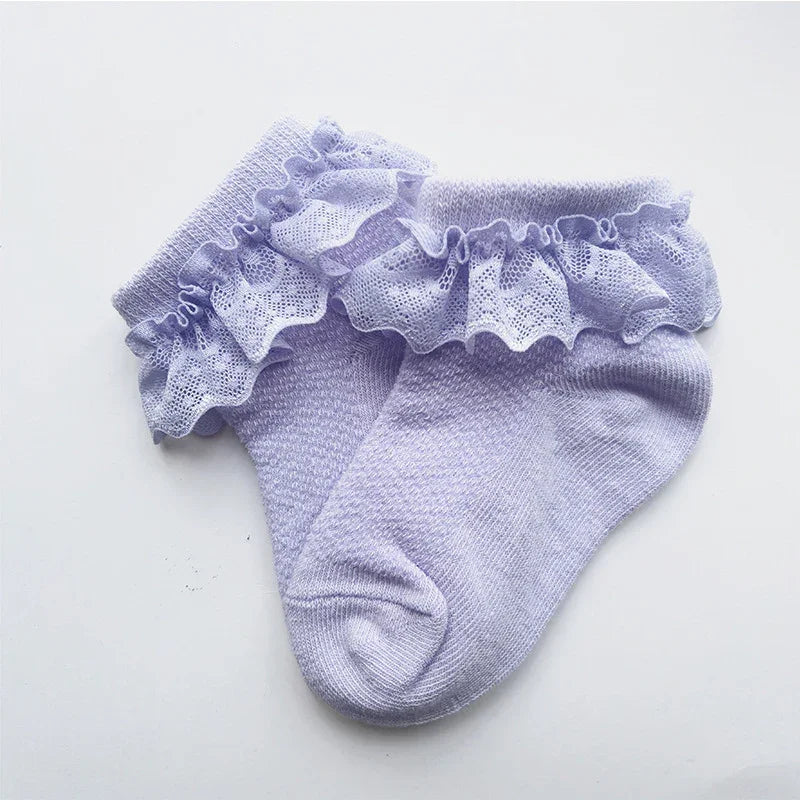 Pair of lavender ankle socks with delicate lace ruffle cuffs on a white background