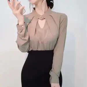 Woman wearing a stylish taupe blouse with a cutout neckline and black high-waisted skirt