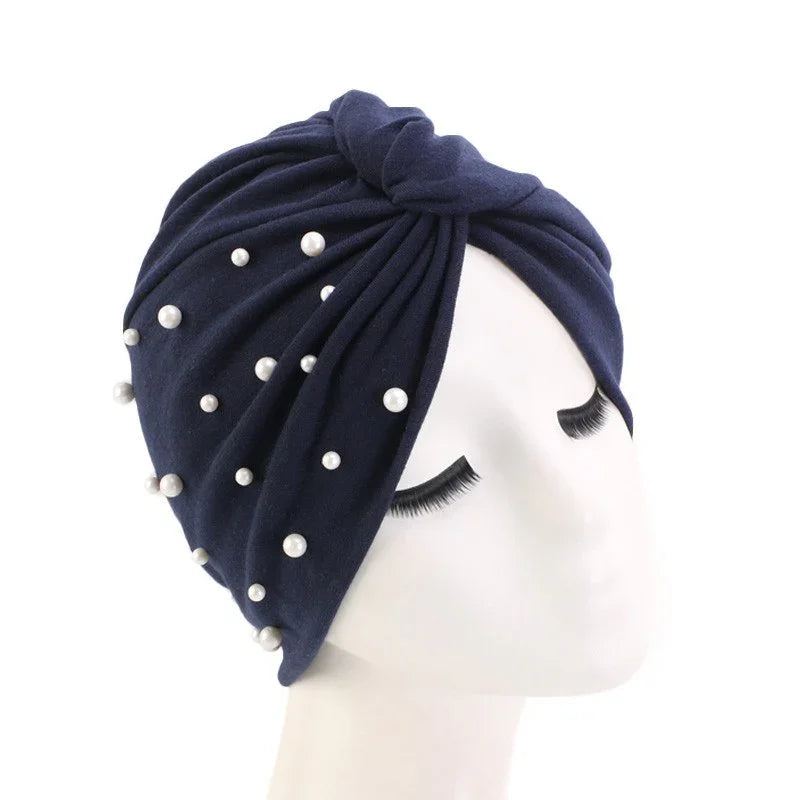 Navy blue turban headwrap decorated with white pearls on white mannequin head