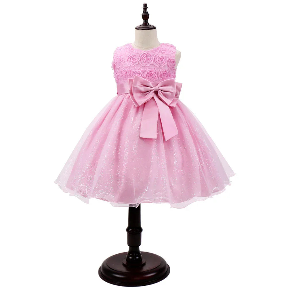 Pink toddler dress with floral bodice, large bow belt, and glittery tulle skirt on mannequin