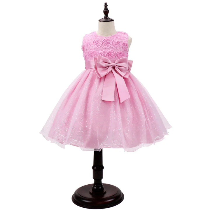 Pink toddler dress with floral bodice, large bow belt, and glittery tulle skirt on mannequin