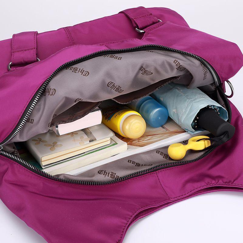 Purple handbag open showing umbrella, sunscreen, small bottles, notebooks, and a yellow keychain inside