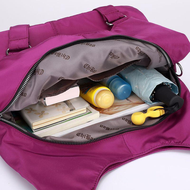 Purple handbag open showing umbrella, sunscreen, small bottles, notebooks, and a yellow keychain inside
