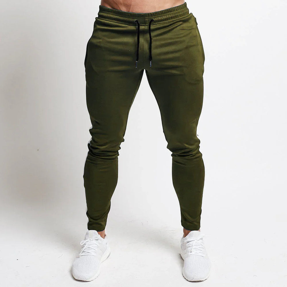 Front view of man wearing olive green slim-fit joggers with black drawstrings and white sneakers