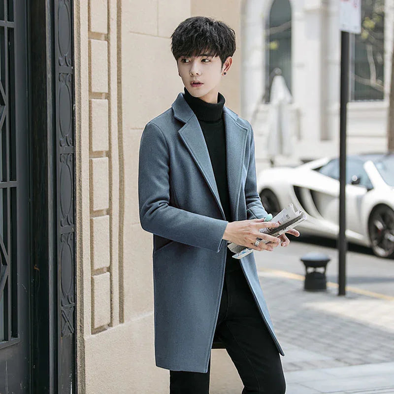 Young man in gray overcoat and black turtleneck holding newspaper on city street with sports car background