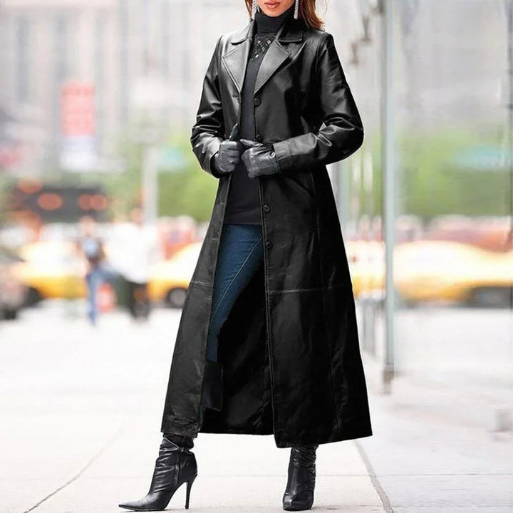 Woman in black long leather coat, gloves, and high-heeled boots on city sidewalk