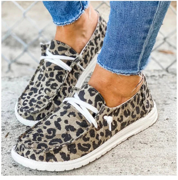 Casual leopard print slip-on shoes with white laces worn with frayed hem blue jeans on concrete