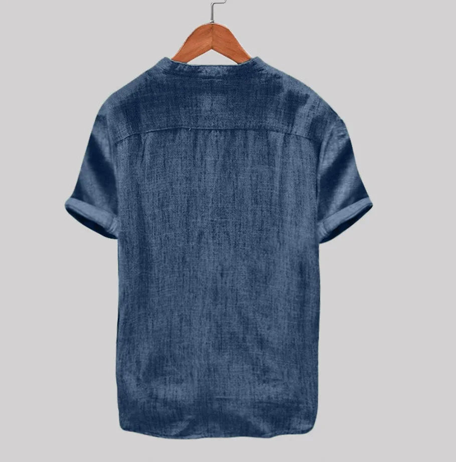 Back view of short-sleeve blue denim shirt on wooden hanger against gray background
