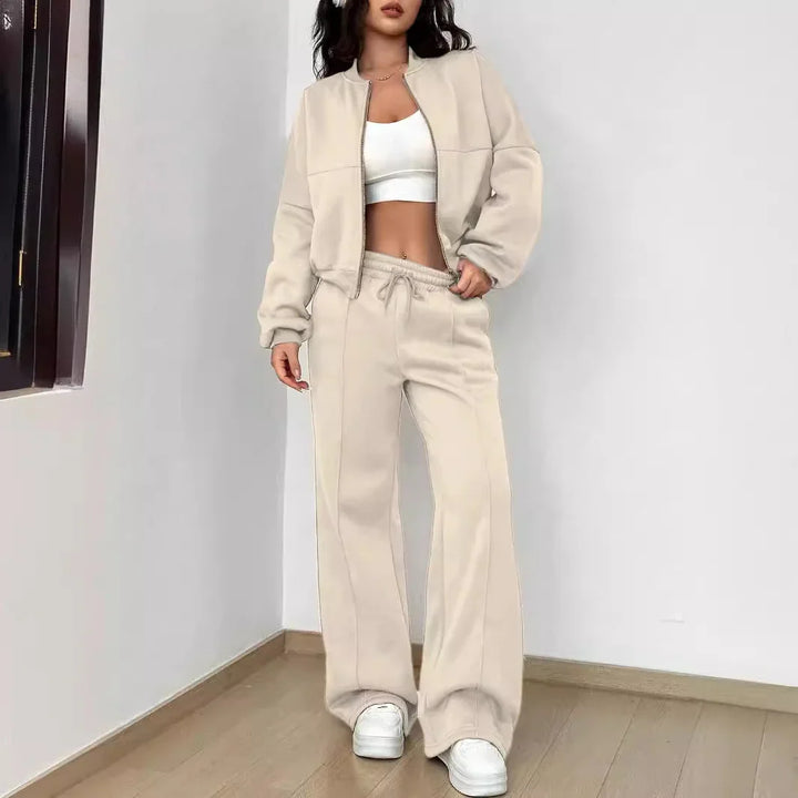 Woman wearing beige zip-up jacket and matching wide-leg pants with white crop top and sneakers indoor