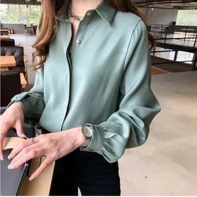Woman wearing sage green silky blouse with buttoned cuffs in modern indoor setting