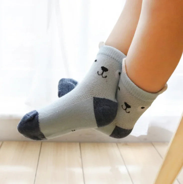 Close-up of feet wearing cute gray and navy bear face socks on wooden floor