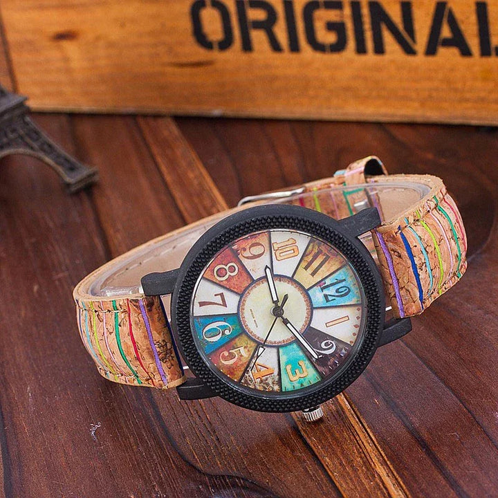 Vintage-style wristwatch with multicolor numbered dial and brown stitched leather strap on wooden surface
