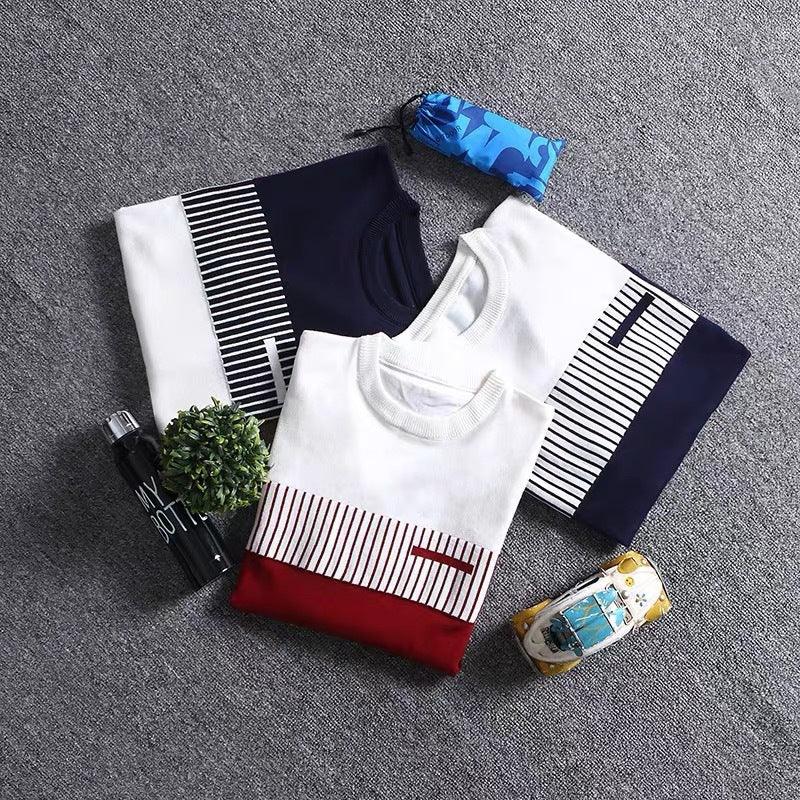 Three striped crewneck sweaters in navy, white, and red laid out on gray carpet with water bottle, plant, and blue pouch