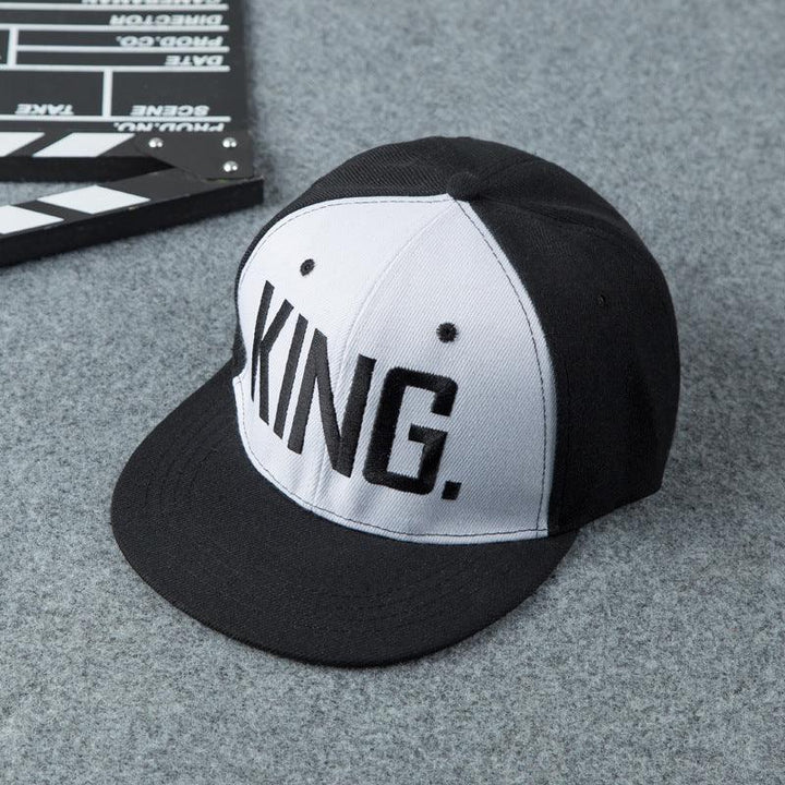 Black and white baseball cap with bold KING text on front panel on grey surface