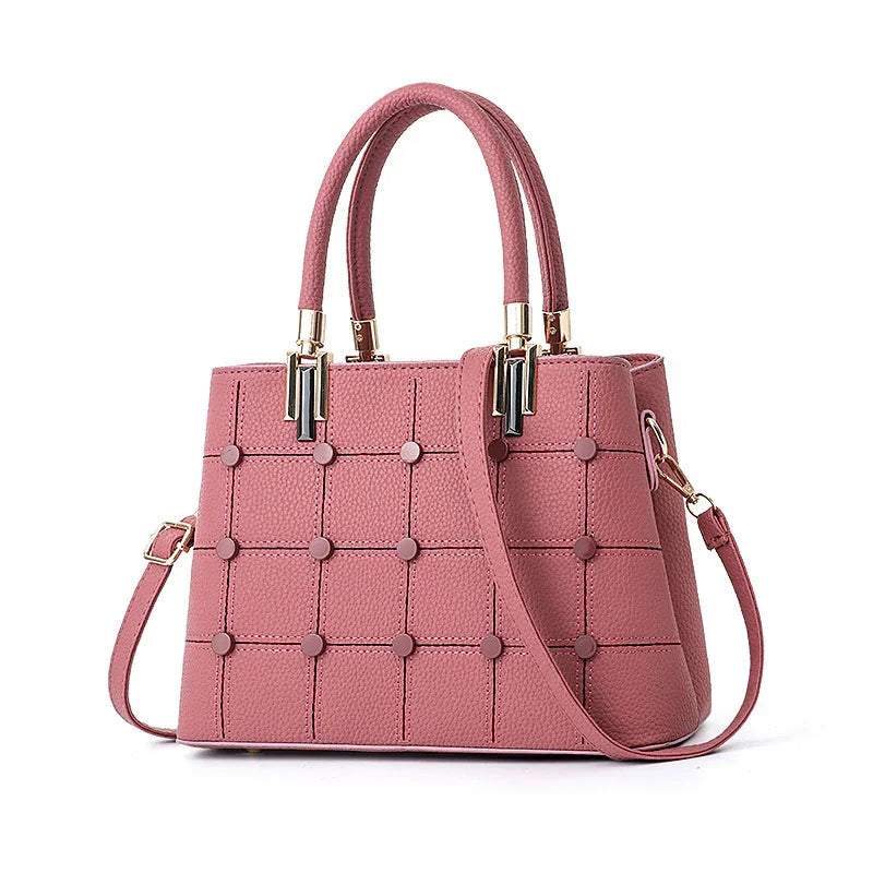 Pink textured leather handbag with top handles, gold accents, and detachable shoulder strap