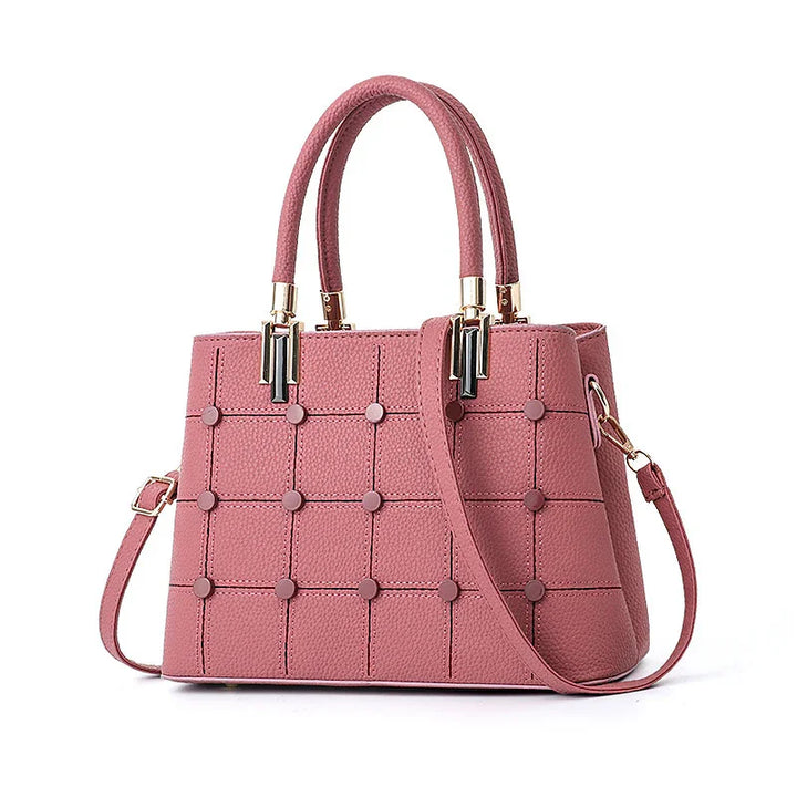 Pink textured leather handbag with top handles, gold accents, and detachable shoulder strap