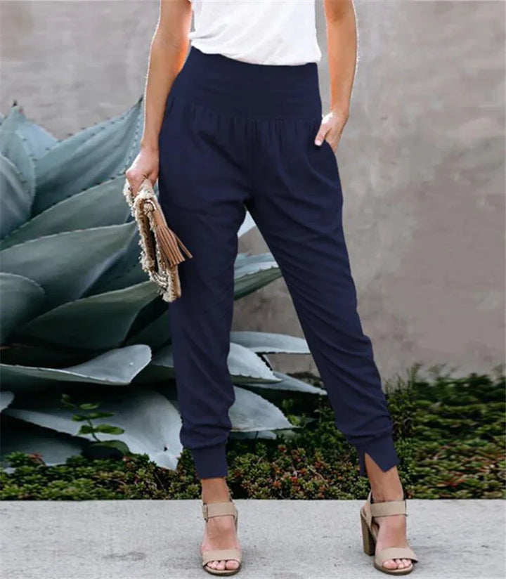 Woman wearing navy blue high-waisted jogger pants with ankle cuffs and beige high heel sandals outdoors