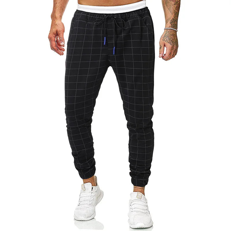 Men's black checkered jogger pants with drawstring waist and white sneakers on model