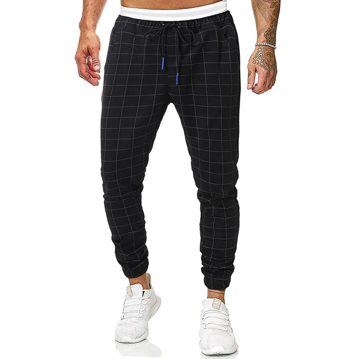 Men's black checkered jogger pants with drawstring waist and white sneakers on model