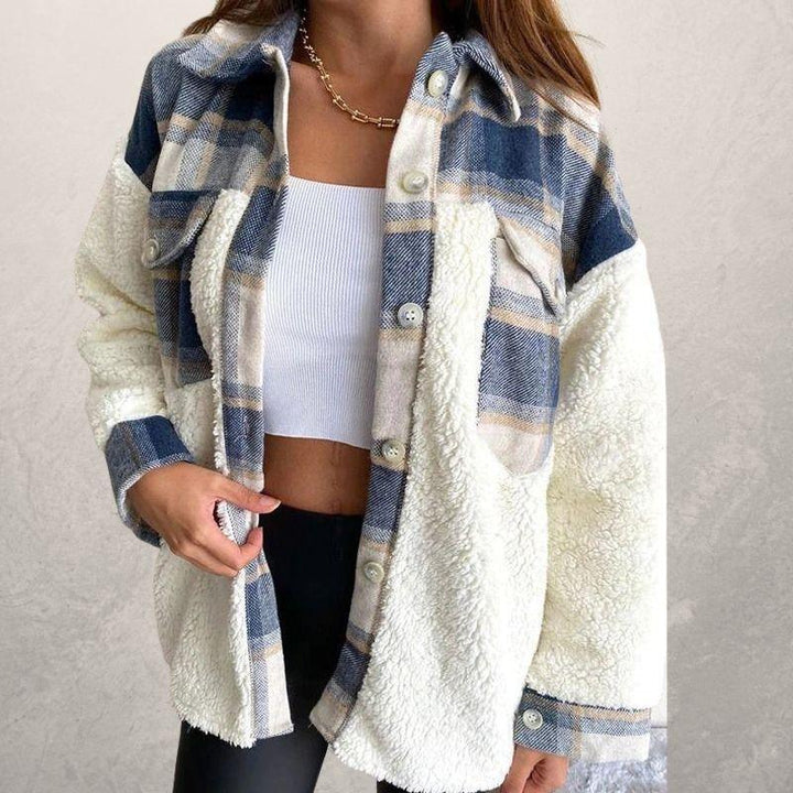 Woman wearing blue and beige plaid sherpa fleece jacket over white crop top with gold chain necklace