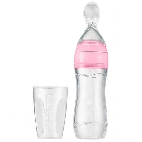clear baby feeding bottle with pink collar and clear measuring cup on white background