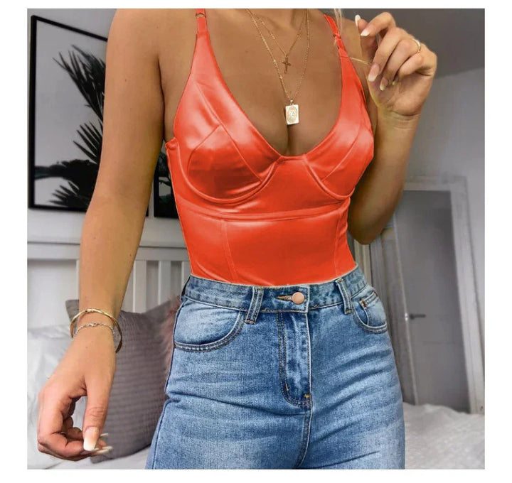 Woman wearing bright orange satin bustier top paired with high-waisted blue denim jeans in cozy indoor setting