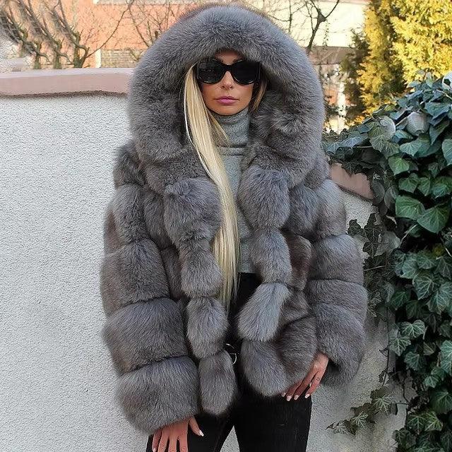 Woman wearing oversized gray fur coat with hood and black sunglasses outdoors