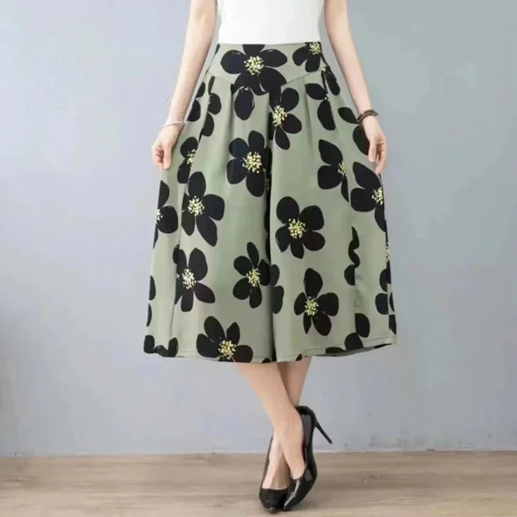 woman wearing olive green wide-leg culottes with large black floral print and black high heels