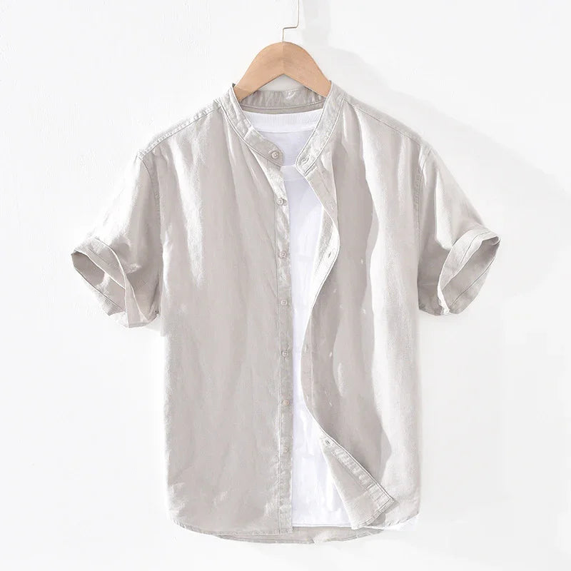 Beige short-sleeve button-up shirt with rolled cuffs over white t-shirt on wooden hanger