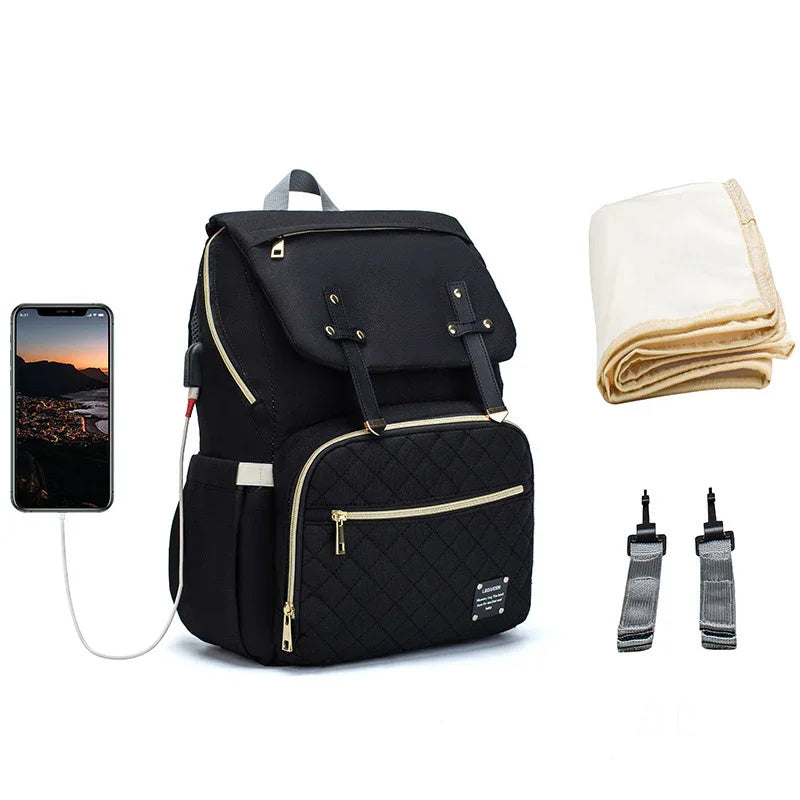Black quilted diaper backpack with USB charging port, cream changing mat, and two stroller straps
