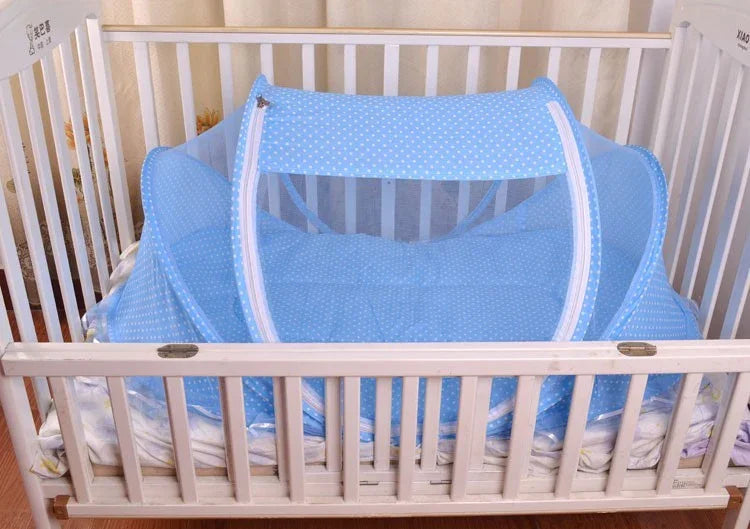 White baby crib with blue polka dot mosquito net tent inside on mattress