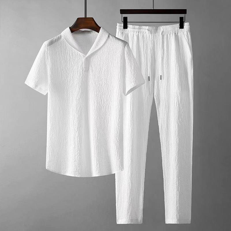White textured short-sleeve shirt and matching drawstring pants set hanging on dark wooden hangers