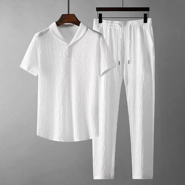 White textured short sleeve shirt and drawstring pants set on wooden hangers against gray background