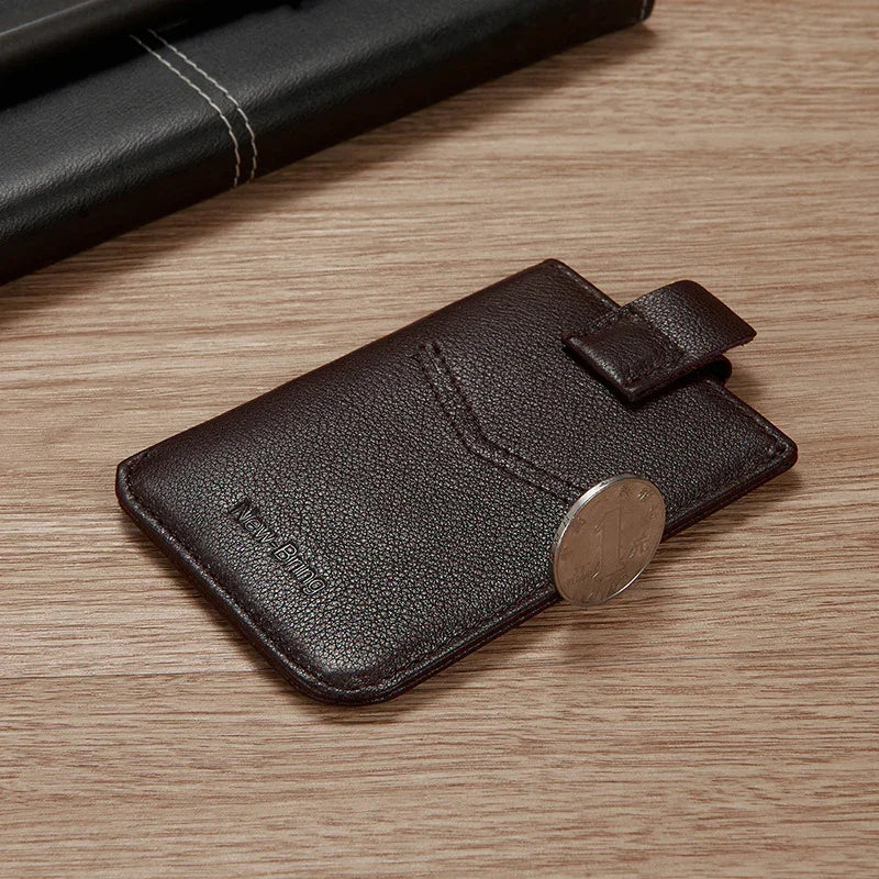 Dark brown leather card holder with pull tab on wooden surface and black leather item in background