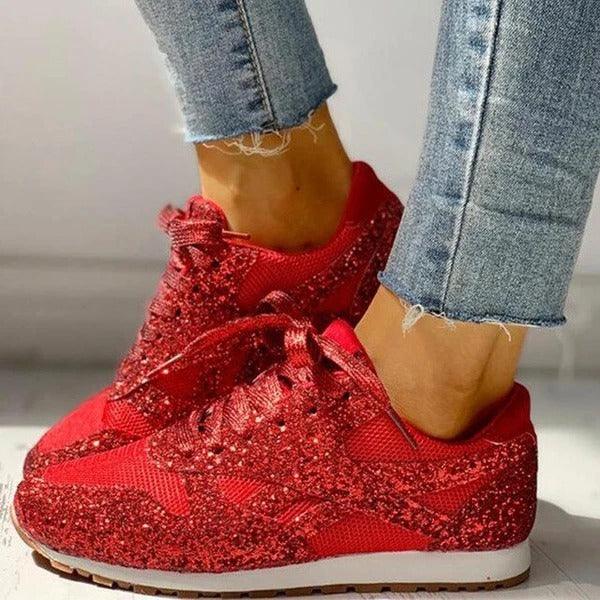 Close-up of feet wearing red glittery sneakers paired with frayed hem blue jeans