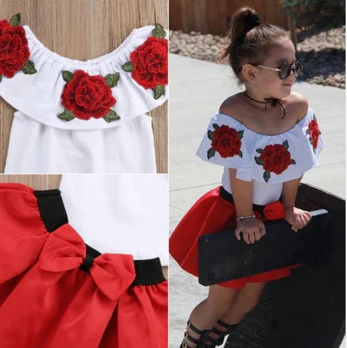 Little girl wearing white off-shoulder top with red rose embroidery and red skirt with bow