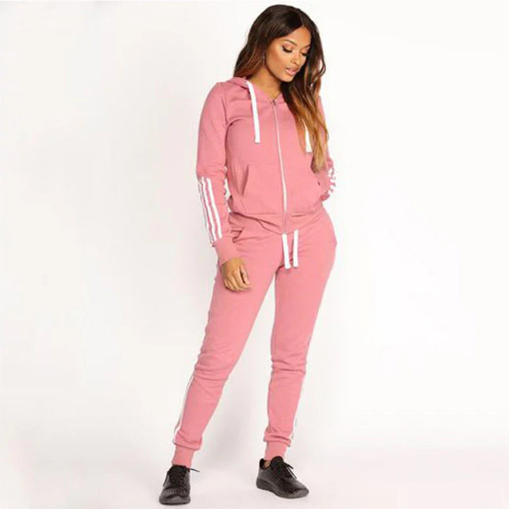 Woman wearing pink zip-up hoodie and matching joggers with white stripes and black sneakers
