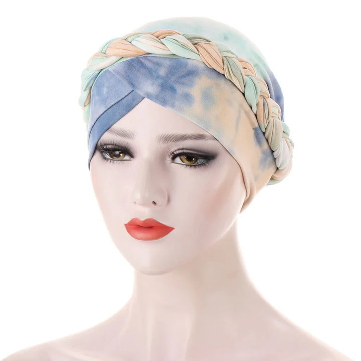 Mannequin head wearing pastel tie-dye turban headwrap with braided detail and smoky eye makeup