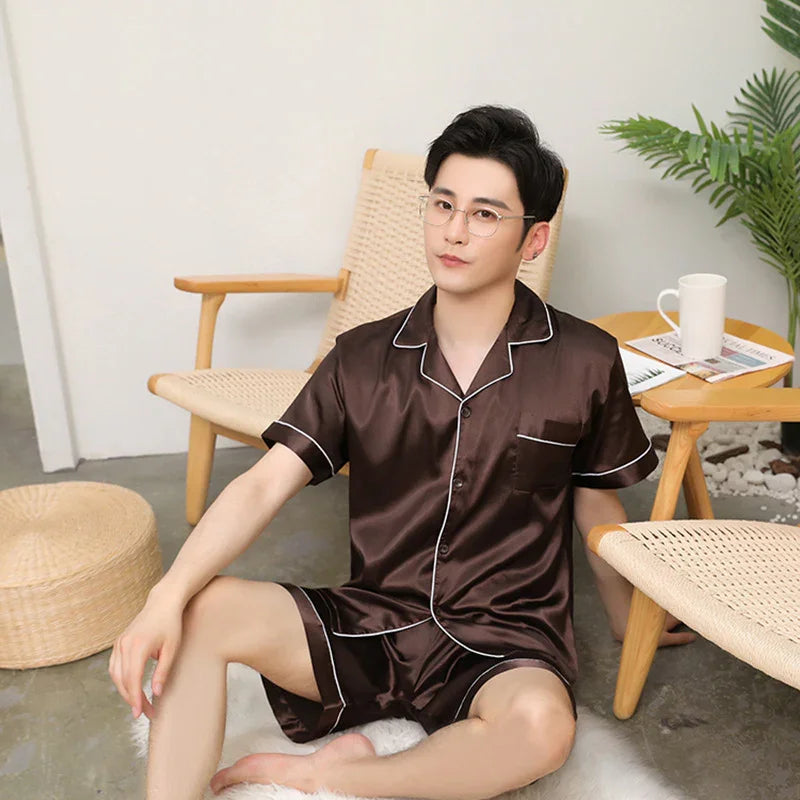 Man wearing dark brown satin short sleeve pajamas sitting on floor in modern living room