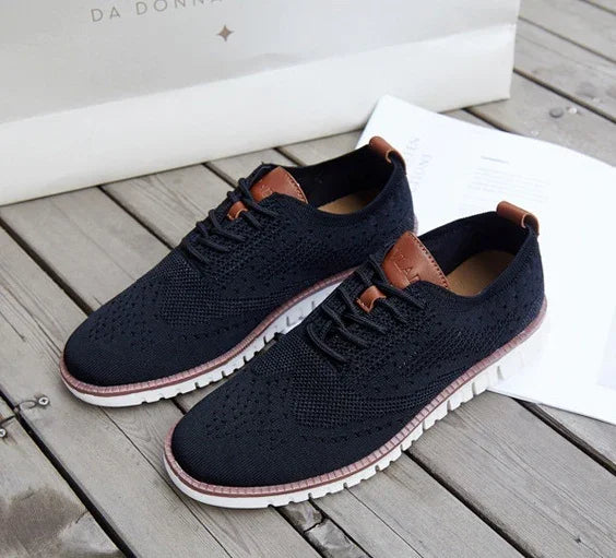 black knit casual shoes with brown leather accents and white soles on wooden floor