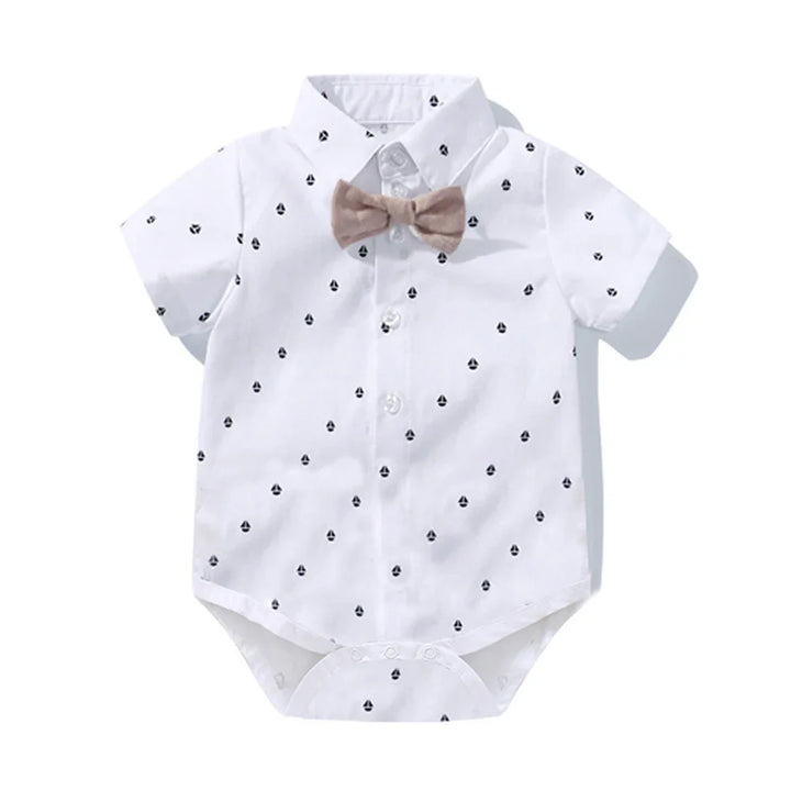 White baby romper with black heart patterns and attached beige bow tie on short sleeves