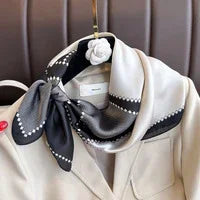 Elegant black and white polka dot silk scarf tied on beige blazer hanger