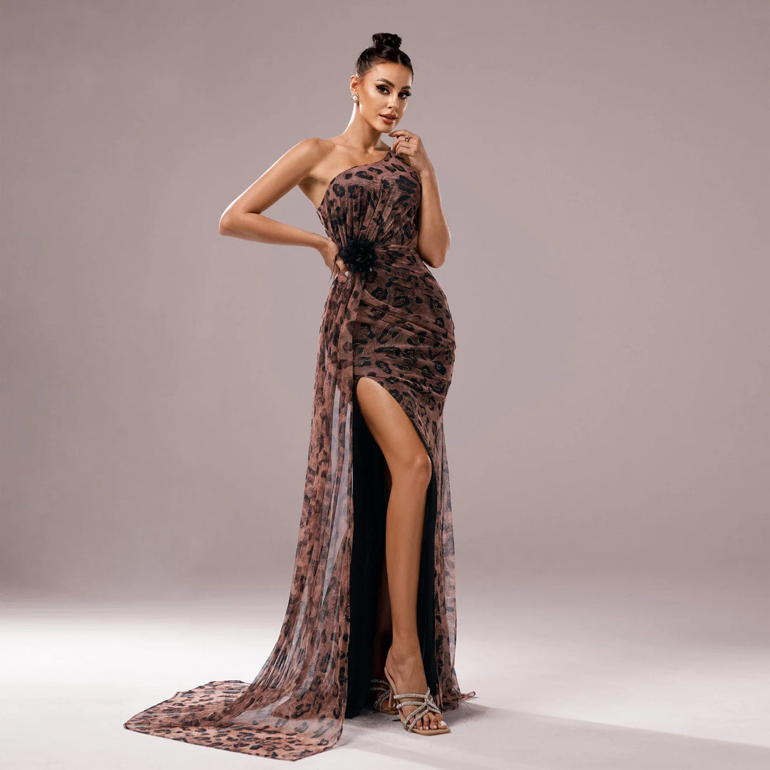 Woman wearing a one-shoulder leopard print evening gown with a thigh-high slit and black detail