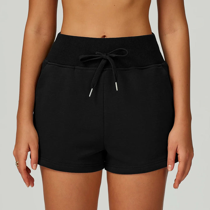 Close-up of woman wearing black high-waisted drawstring casual shorts on light background