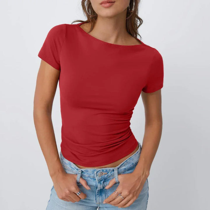 Woman wearing a fitted red short-sleeve top paired with light blue jeans against white background