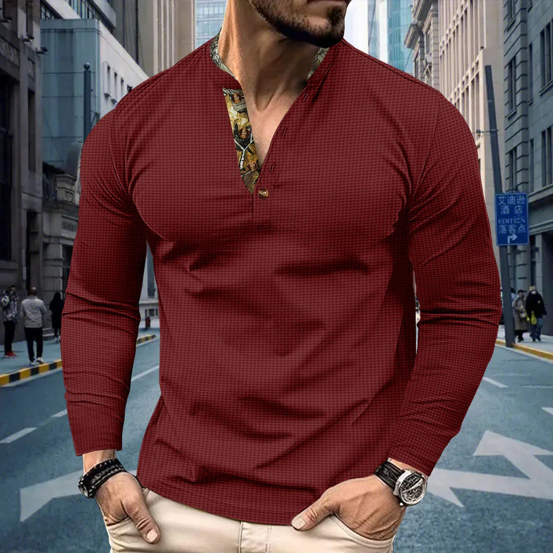 Man wearing maroon long-sleeve henley shirt with patterned collar standing on urban street