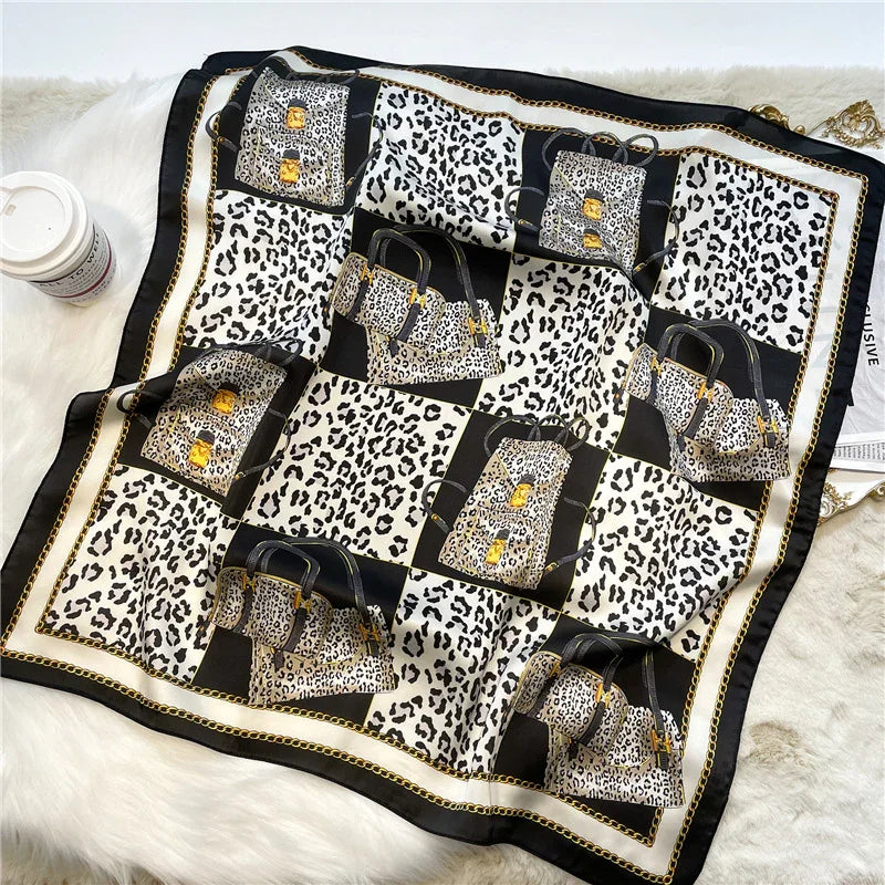 Silk scarf with leopard print and handbag pattern featuring black, white, and gold chain border on white fur background