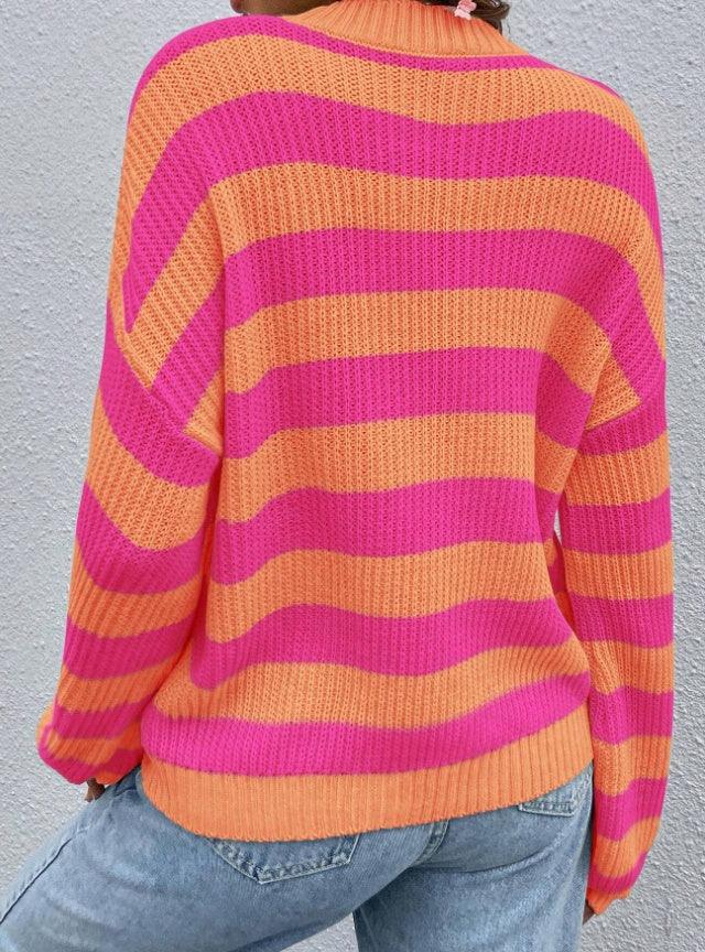 Back view of person wearing vibrant pink and orange striped knit sweater with light blue jeans