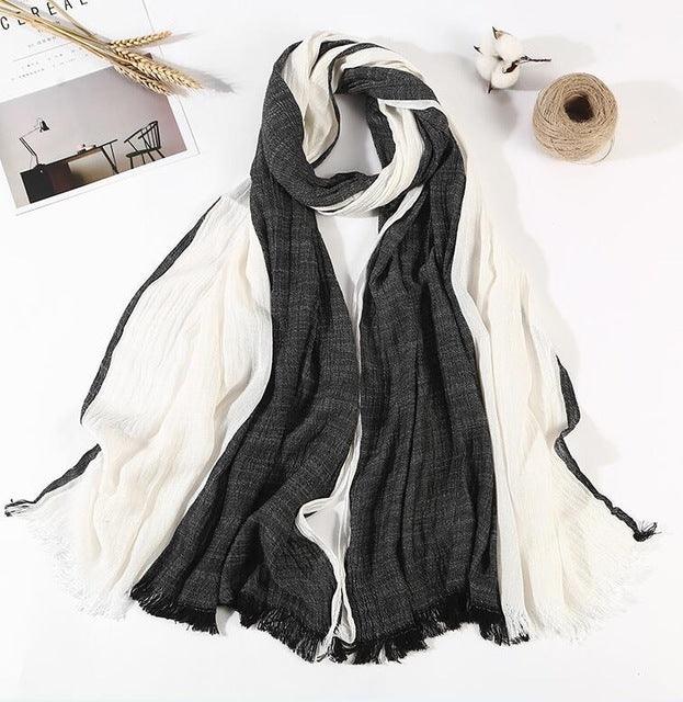Black and white lightweight striped scarf with fringed edges displayed on white background with decor